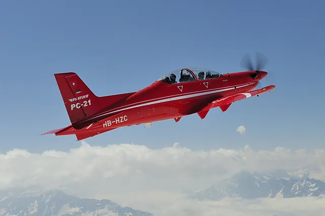 Pilatus PC-21 in flight over snow-covered Alpine peaks.